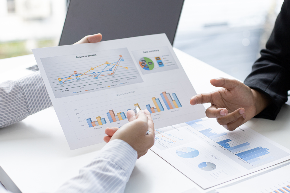 An image of two business leaders discussing a printed report showing business growth as a line chart and bar chart.