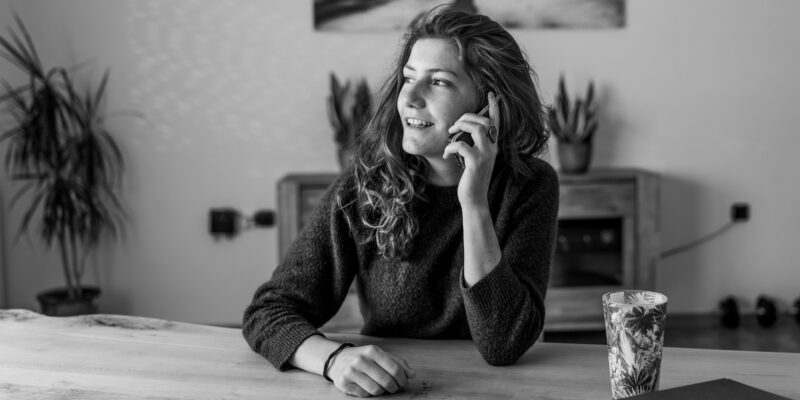 Business woman smiling whilst on a call: Business mentoring discovery calls help you understand what the client wants and get aligned with them.