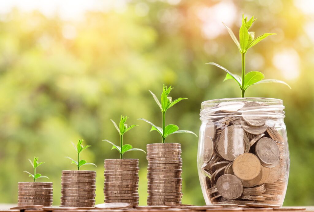Image showing five stacks of coins, each with a seedling growing in it, with a big jar of them at the end.